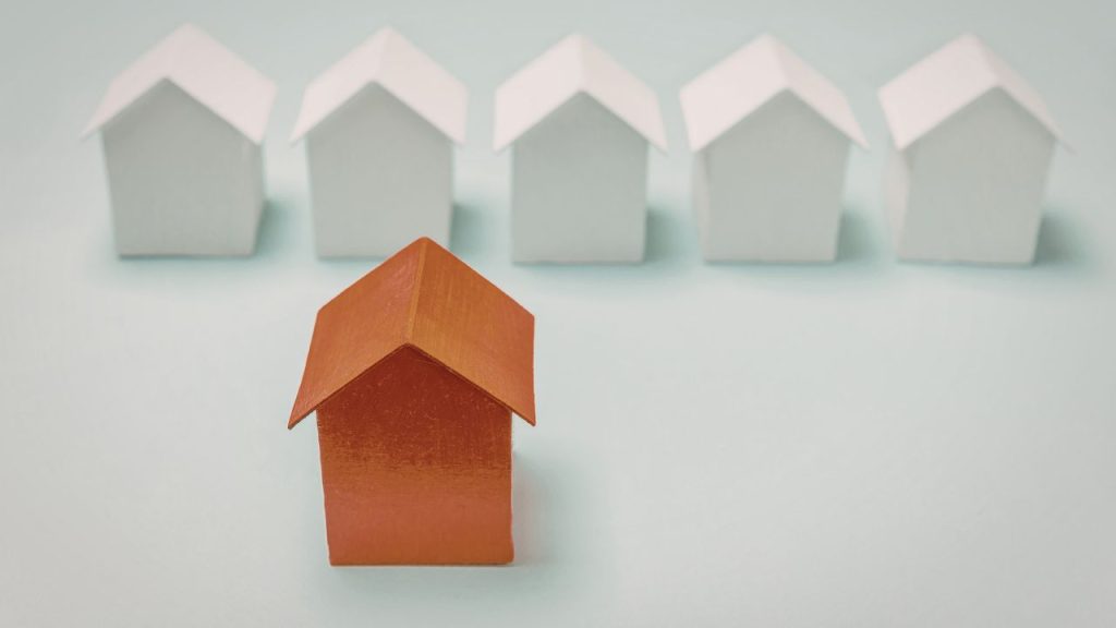 a red house figurine in front of a bunch of smaller ones