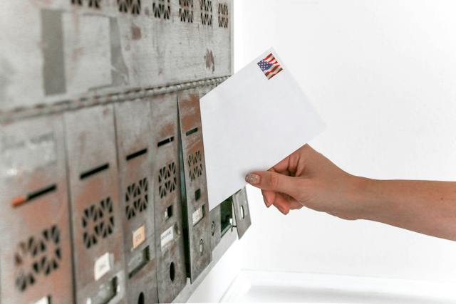 Hand placing a letter into a community mailbox so send a notice of failure to pay rent