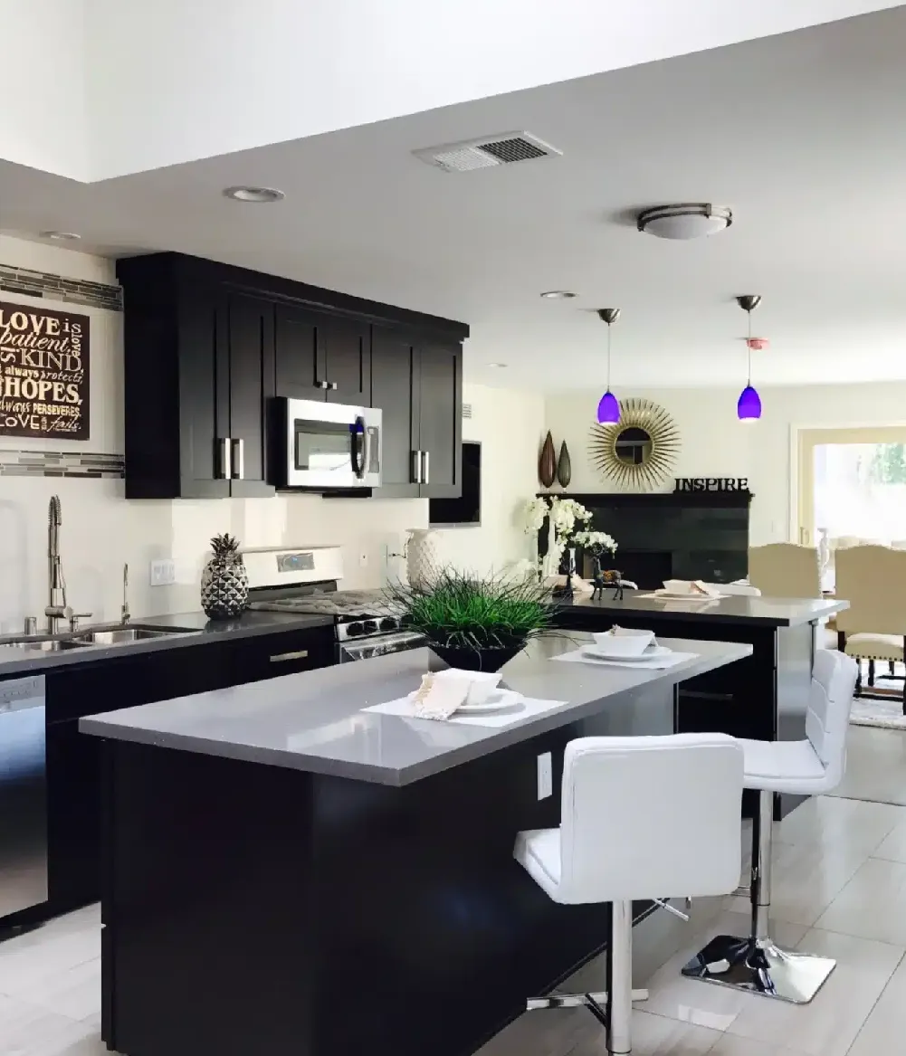 A kitchen with black cabinets and white counters