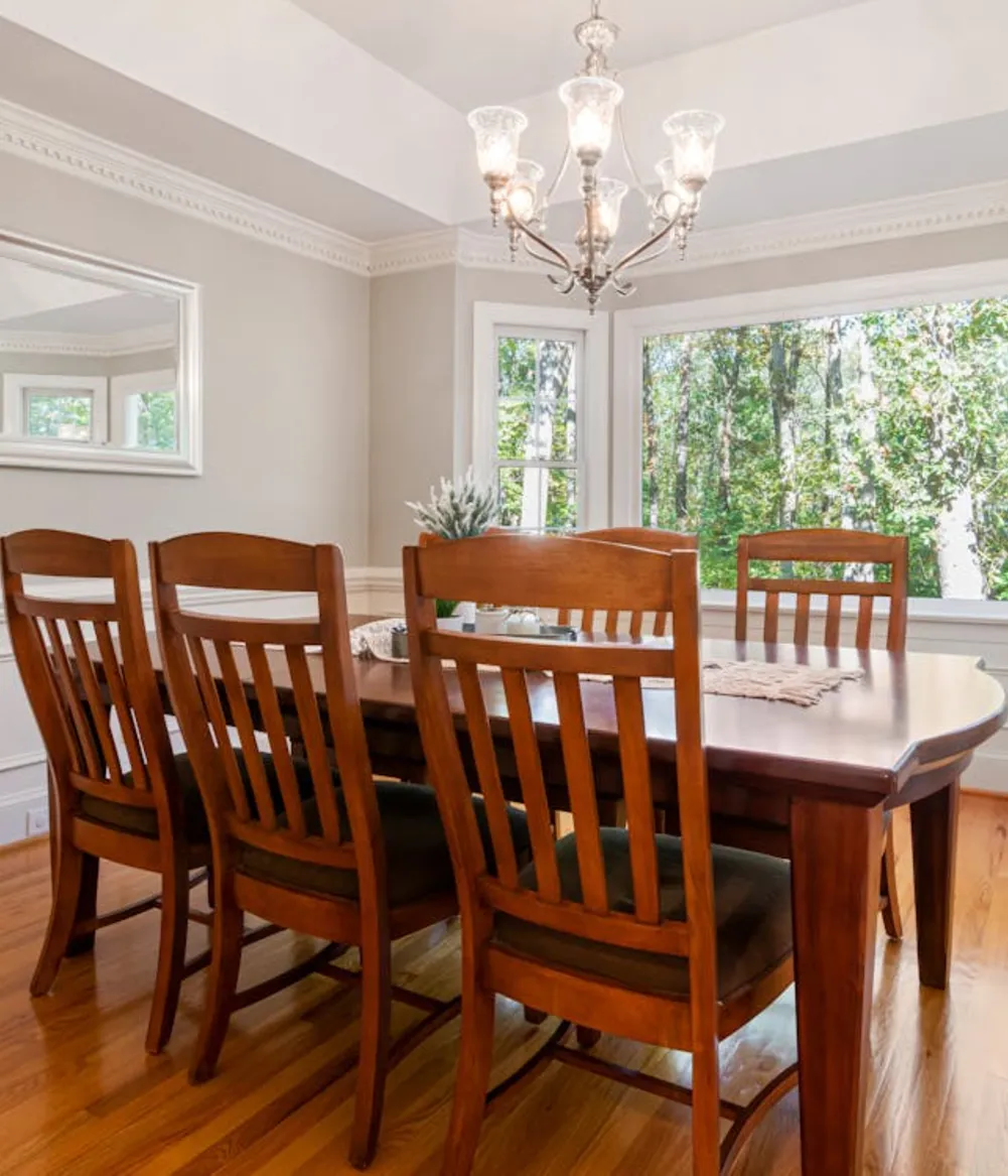 A white dining room with dark wooden table and large chandelier