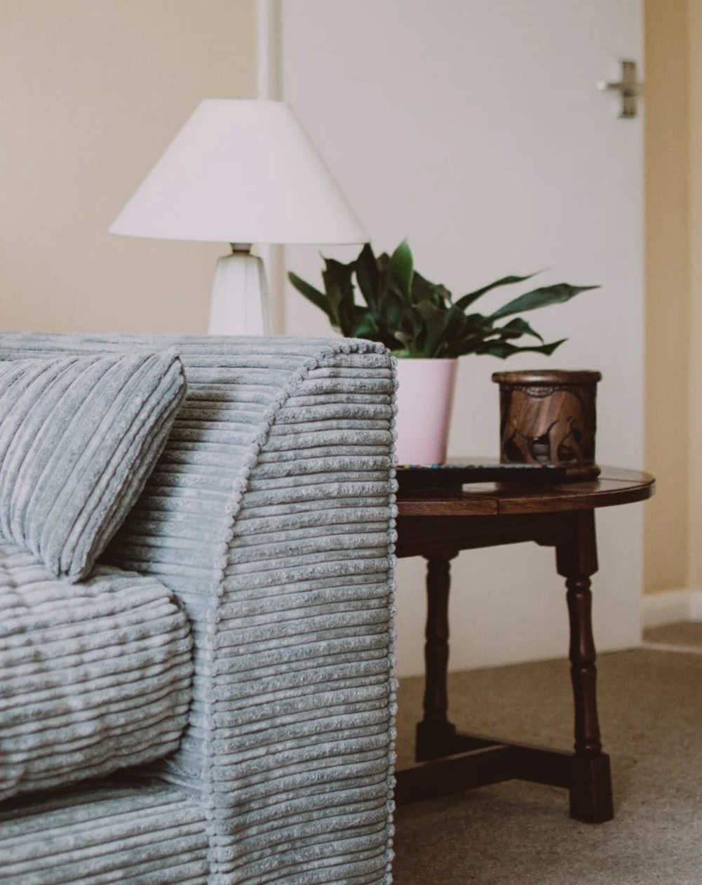A blue-grey couch and a dark wood side table