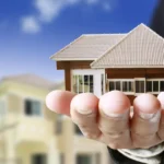 Man holding model home in palm of hand