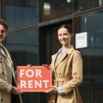 Two people holding a For Rent sign
