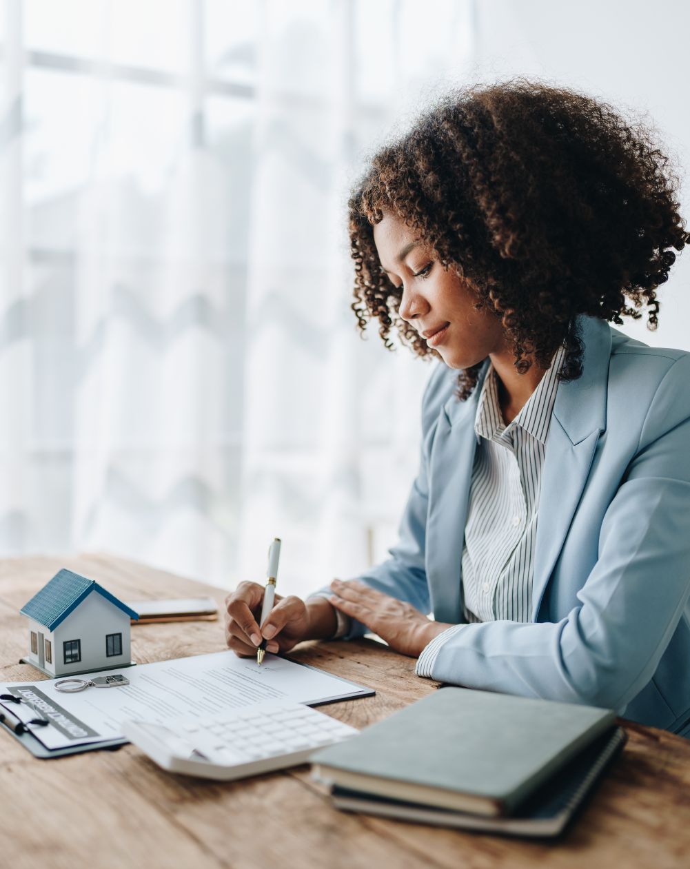A female real estate professional sitting at a desk signing paperwork