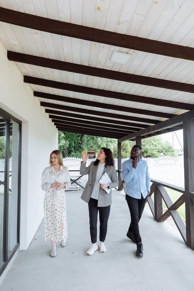 Three people tours the outside on a home