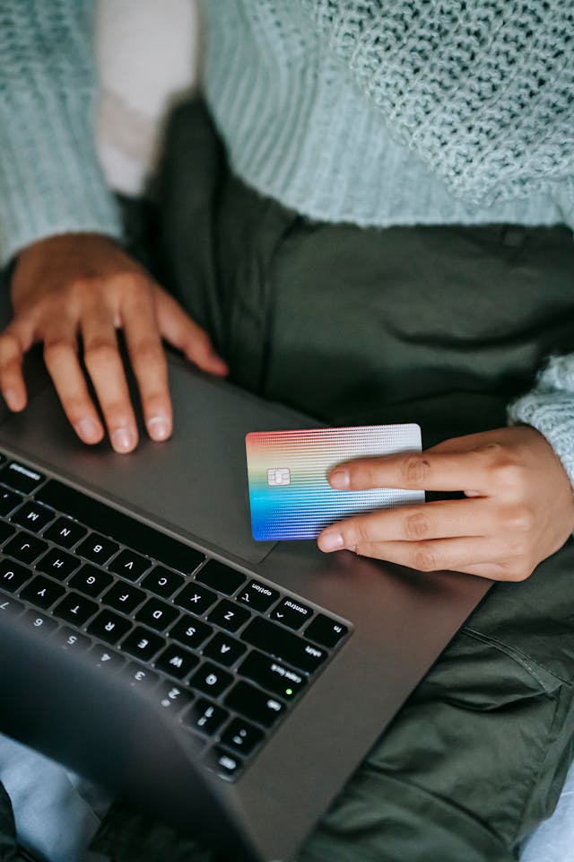 a person holding a credit card and their laptop to make an online payment