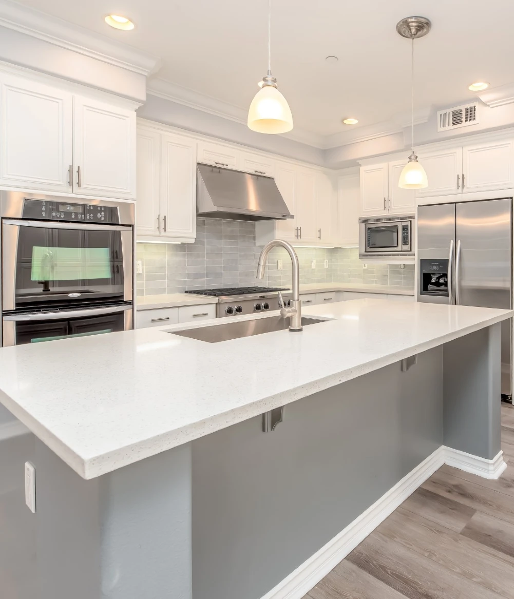 a white kitchen with a grey island in the middle