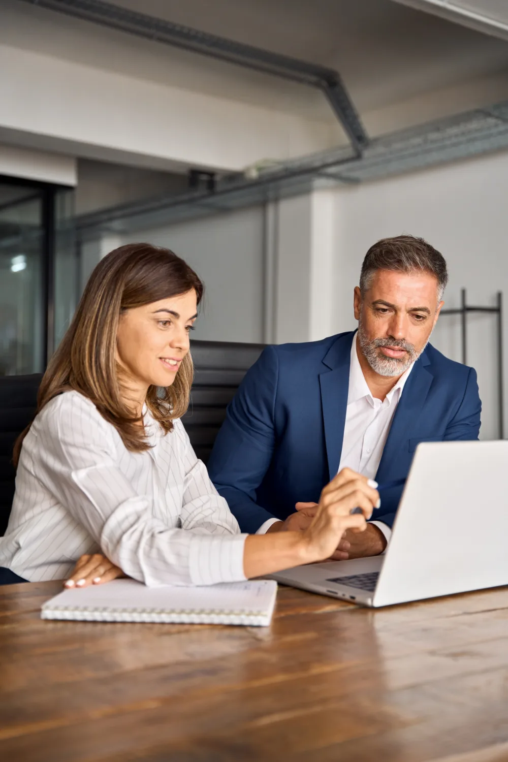 A middle-aged businessman and businesswoman working together on a laptop 