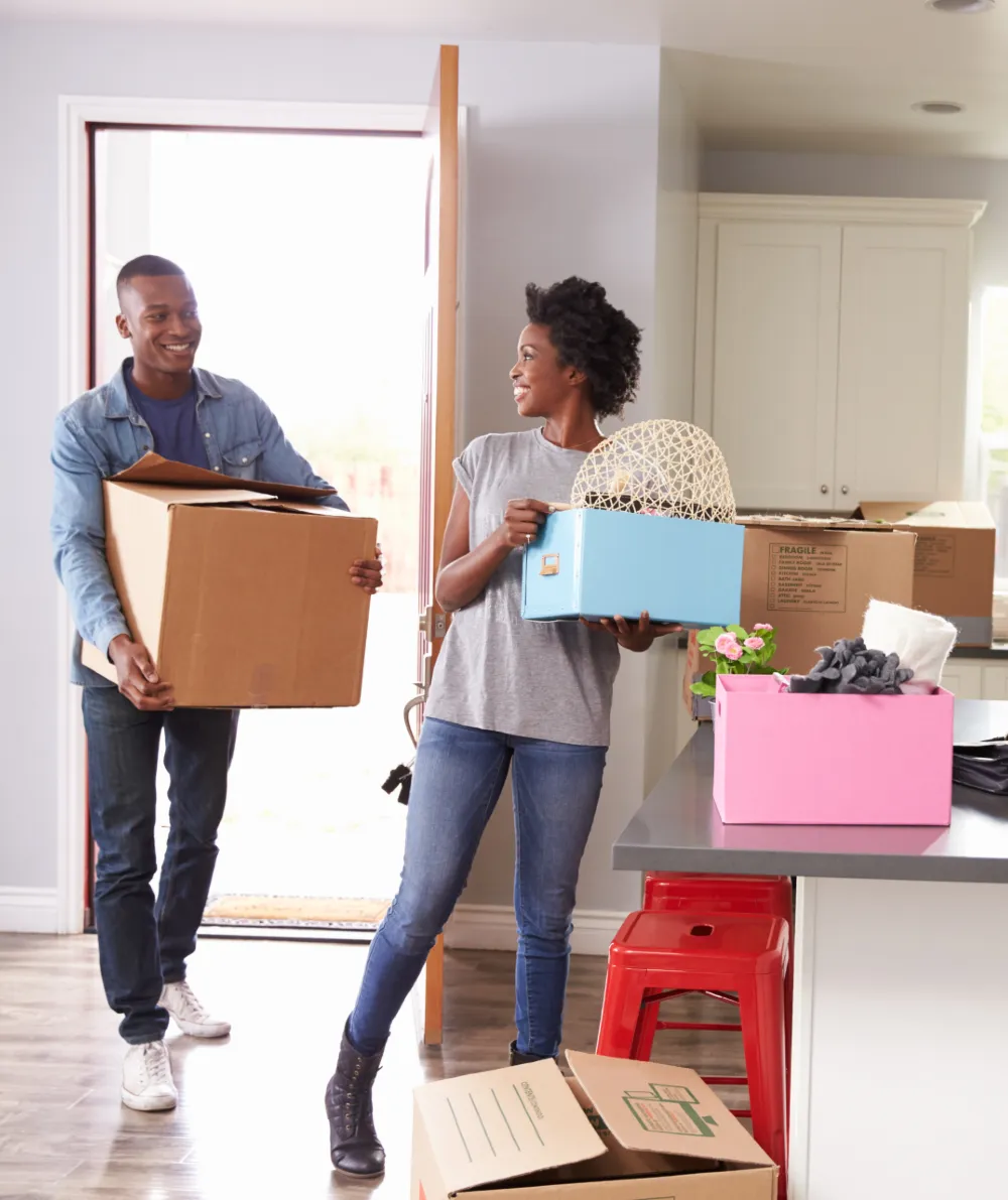 A young couple moving in and carrying boxes into their new kitchen