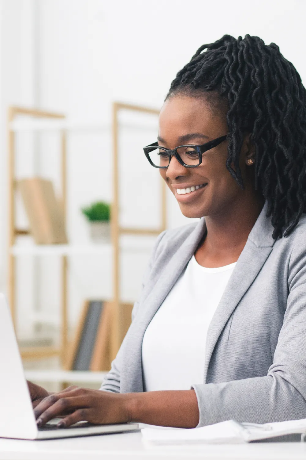 A young female office manager smiling and typing on a laptop