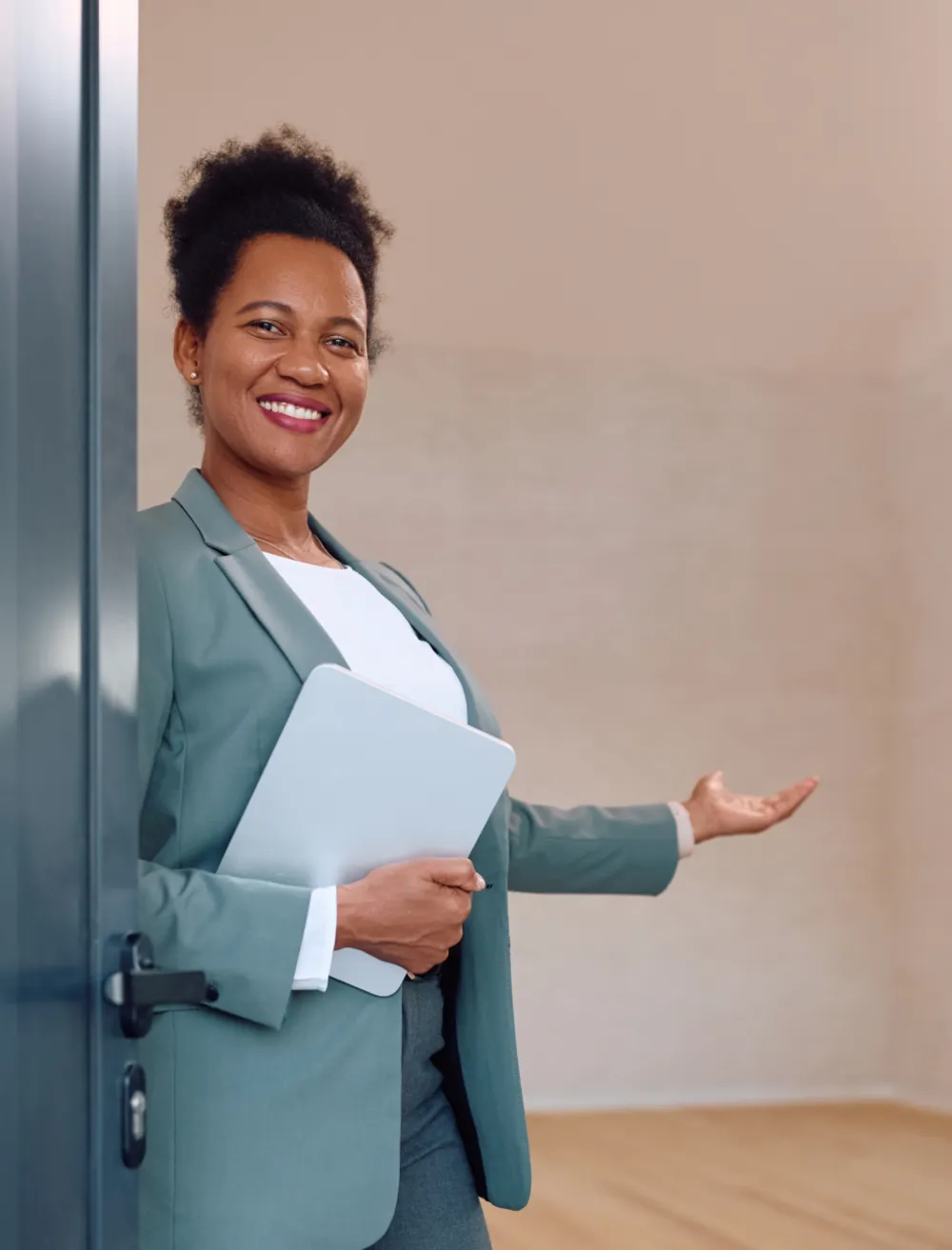 A female property manager standing in the doorway of an empty apartment gesturing with her hand