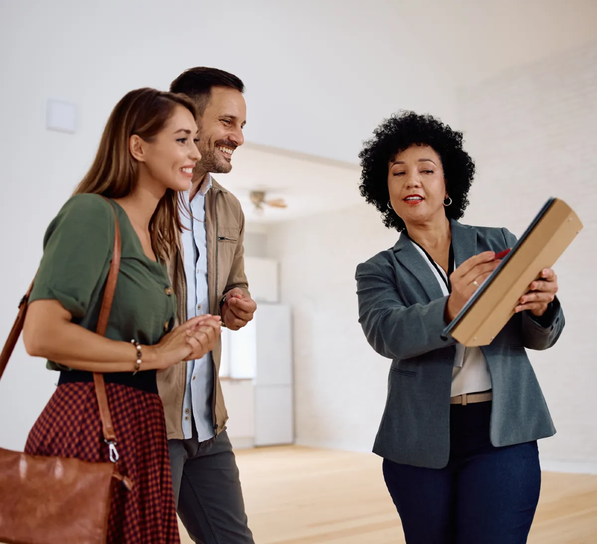 A property manager showing a young couple an apartment and pointing to clipboard