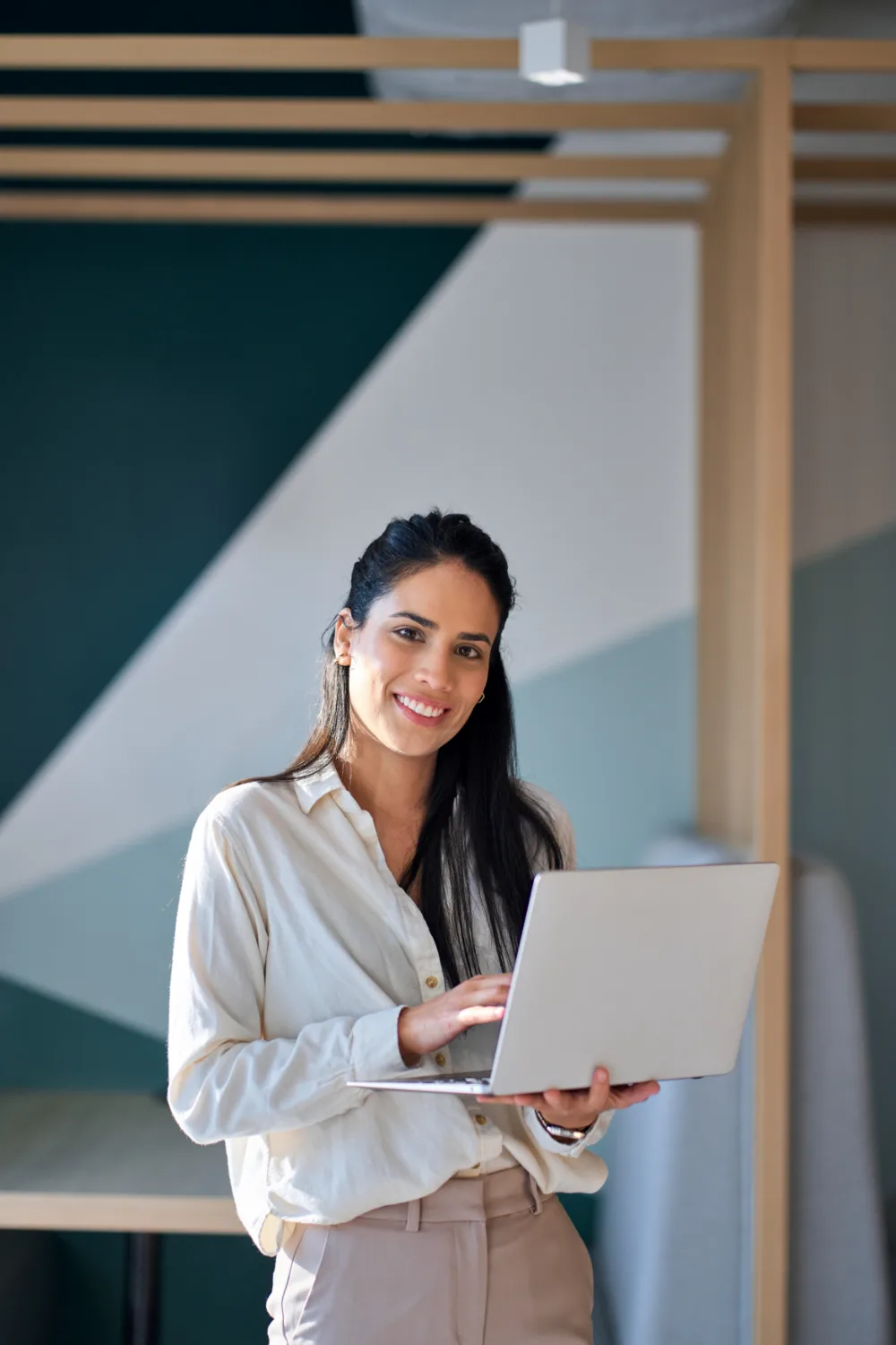 A young woman smiling standing with a laptop in hand