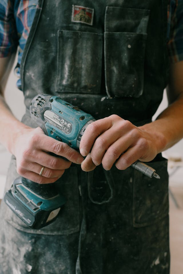 A contractor in a work apron holding a drill