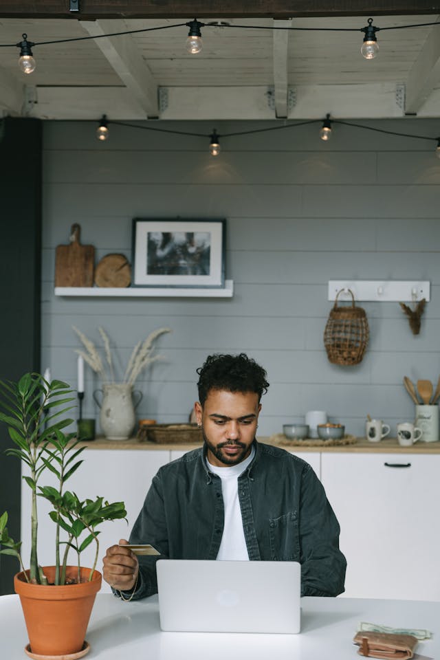 person sitting in front of their computer holding a credit card