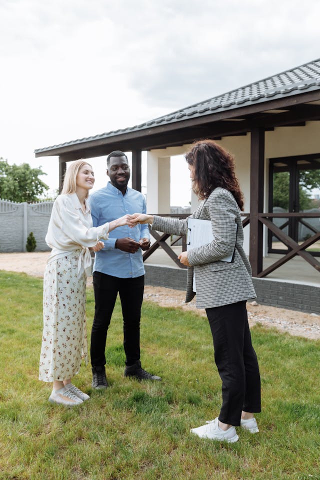 a real estate agent handing two people the keys to their new rental