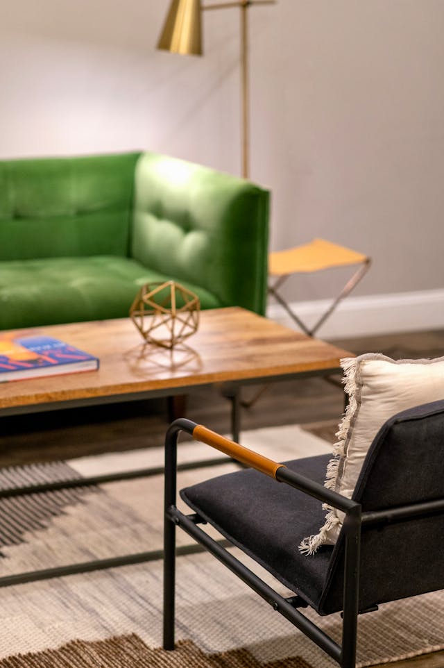 a living room with a green couch, wooden coffee table and a small armchair