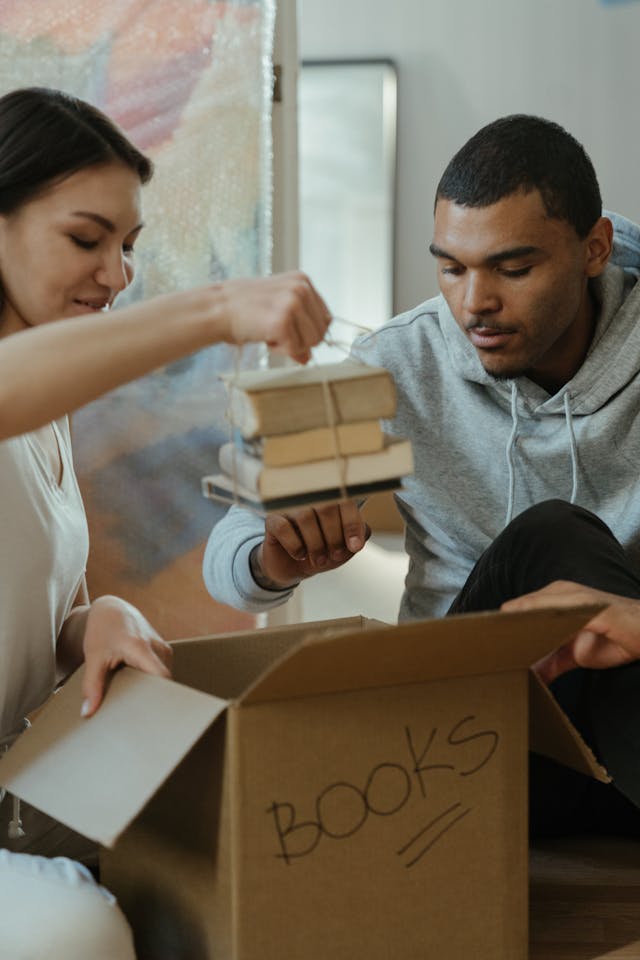 two people unpakcing a moving box with books in it