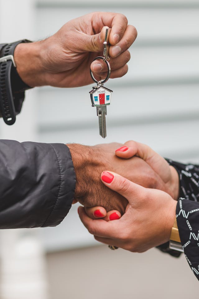 two people exchanging house keys and shaking hands