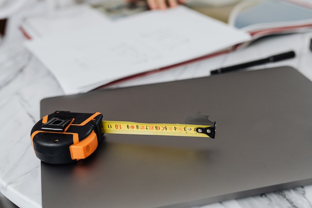 measuring tap on top on a laptop with blueprints scattered
