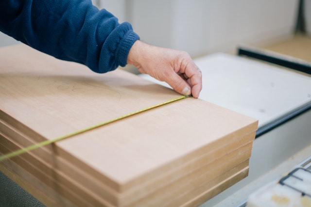 person using a measuring tap on a piece of wood